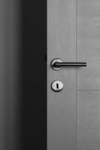 Close-up of a modern gray door with a sleek metal handle and keyhole.
